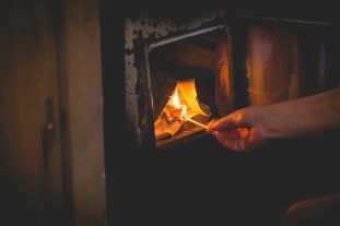 Lighting up the stove in a wood-heated sauna.