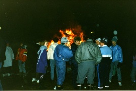 People socializing while the bonfire is burning in the background.