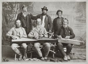Black and white picture of six serious kantele players posing at the camera.