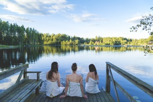 Women sitting on the pier, looking towards a lake.