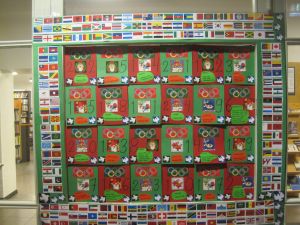 Punavihreä joulukalenteri, jota koristaa olympiarenkaat ja eri maiden liput.