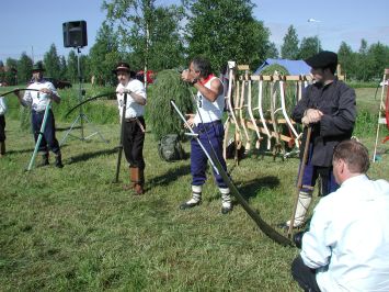 Viisi ihmistä seisoo viikatteet kädessä.