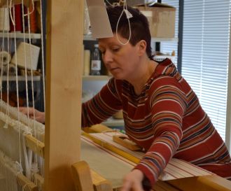 A person using a loom to weave fabric.