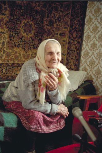 Vanha rouva laulamassa runoa.