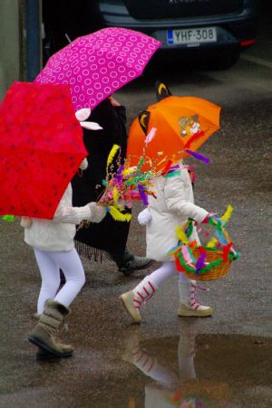 Lapsia virpomassa trulleiksi ja pupuiksi pukeutuneena värikkäiden sateenvarjojen alla.