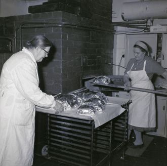 A black and white picture of two bakers baking kalakukko.