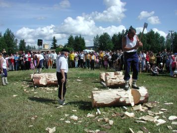 Mies seisoo suuren tukin päällä veistämässä sitä kirveellä.