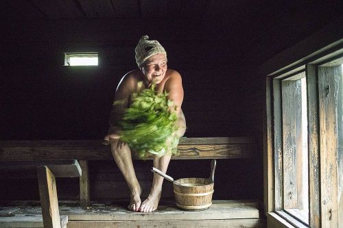 Woman in a sauna with a sauna whisk