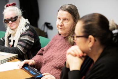 Three people sitting by a desk.