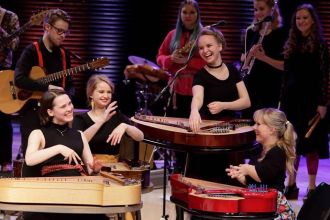 Four laughing kantele players performing.