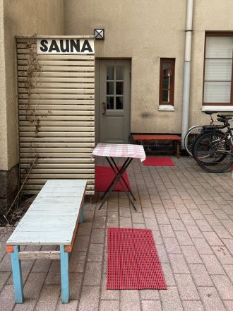 Inner yard of an apartment building with a bench and a sign with the word "sauna".