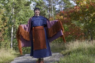 Muinaispuvun nykyversioon pukeutunut iloinen henkilö.