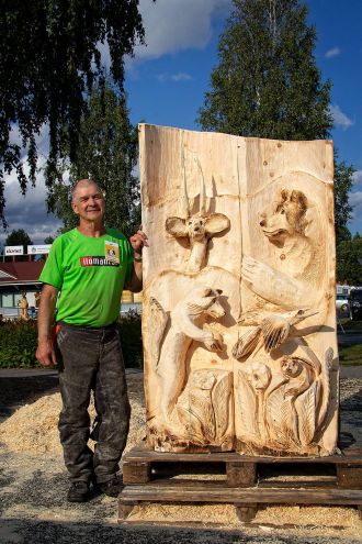Markku Tuominen ja valmis veistos Villi luonto. Veistos valmistui Ilomantsin Karhufestivaalilla 2018 kilpailussa, jonka teemana oli Villi luonto. Kuva Maaseudun Sivistysliiton kuva-arkistosta.