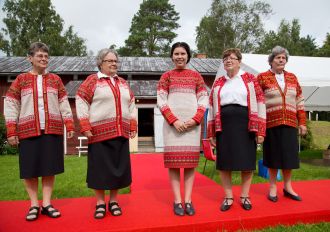 Ihmisiä hymyilemässä kameralle korsnäsipaidat yllään.