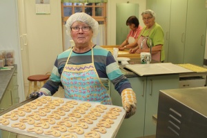 A baker holding a full tray of twists.