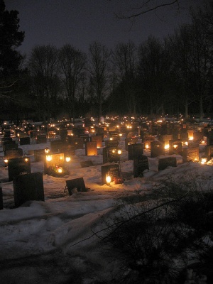 Candles shining in front of graves in the evening.